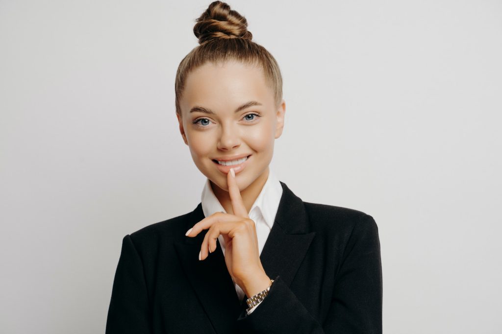 Smiling successful female lawyer in dark suit looking at camera with confident gesture